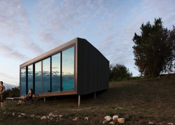 Vue d'un refuge periurbain à la tombée de la nuit avec deux personnes sur la terrase