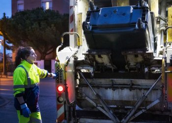 Femme collectant les déchets d'une poubelle au soleil levant avec un camion poubelle