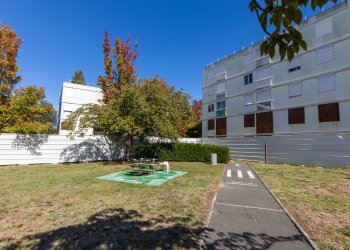 Vue d'une habitation devant un parc un jeu d'enfant et une piste cyclable