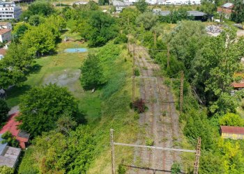 Bue d'une voie ferrée dans la nature avec quelques habitations autour.