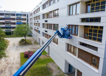 deux hommes travaillent sur une nacelle sur des vitres d'un logement