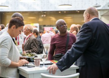 Trois personnes autour d'une table discutent lors d'un colloque