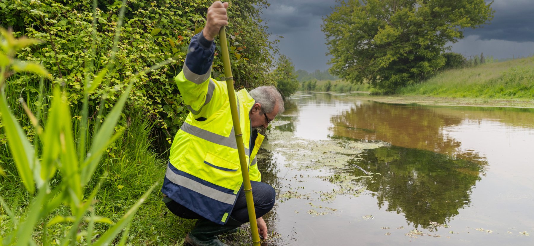 Un technicien rivière effectue une prélèvement dans la Jalle