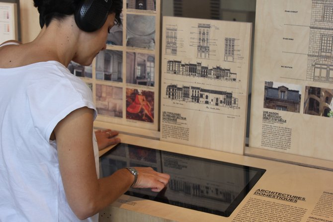 Jeune femme casque audio sur les oreilles utilise un écran tactile dans une exposition historique