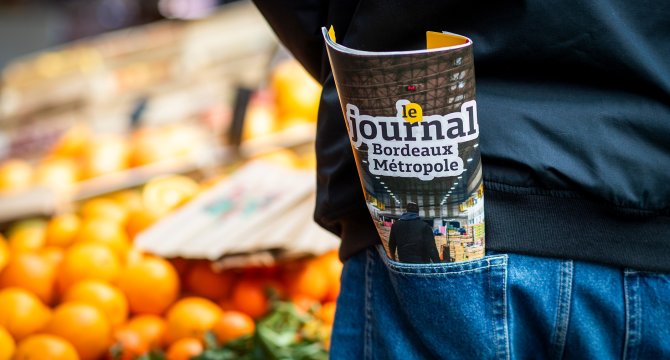 Journal 69 plié dans la poche arrière d'une personne sur un marché 