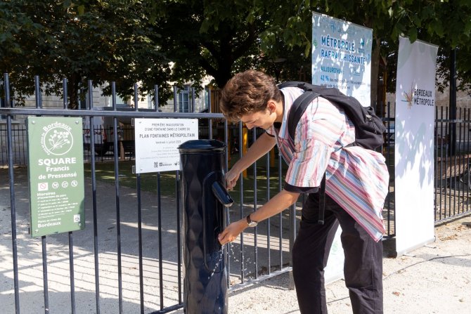 photo d'un usager se servant de l'eau à la fontaine de la place Francis de Pressenssé