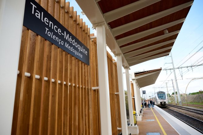 Vue du panneau de la Gare Talence Médoquine depuis les quais avec au fond le TER et les passagers qui montent dans le train