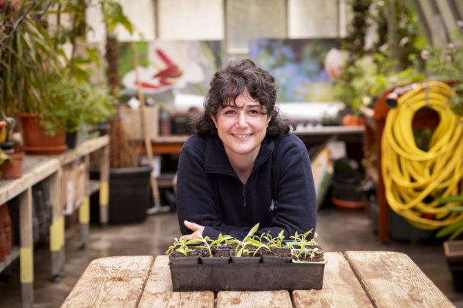 Émilie, animatrice jardinière pose devant un bac contenant des plantes en terre